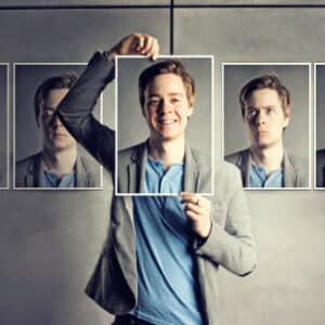 Photo of person holding portraits of himself with different faces and emotions for Emotional Intelligence Workshop